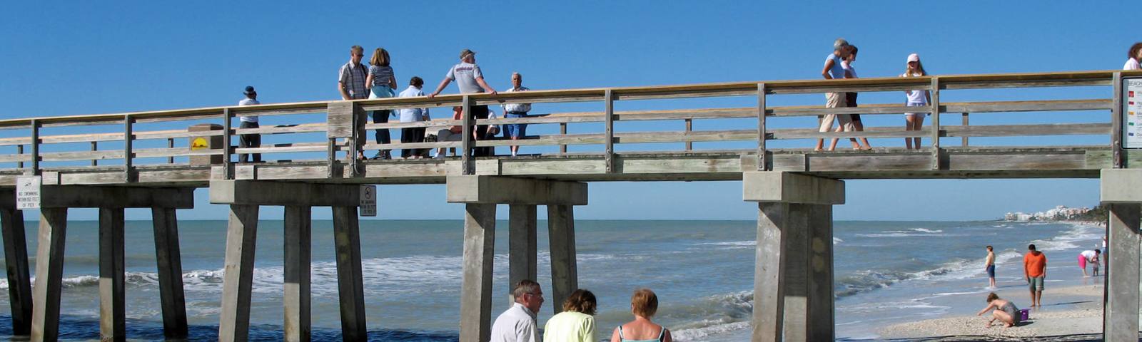 The Naples Pier over the Gulf of Mexico, with people walking on the beach below